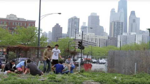 Community members working a garden in front of a city skyline
